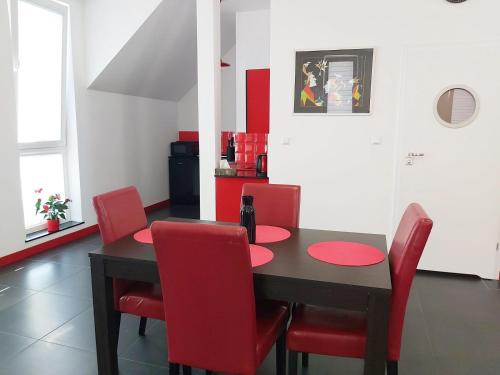 a dining room with a black table and red chairs at Apartament Parkowa 2 in Morąg