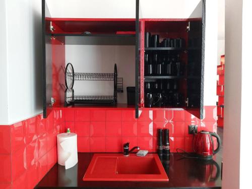 a red kitchen with a sink and a red tile wall at Apartament Parkowa 2 in Morąg