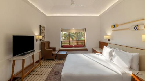 a hotel room with a large bed and a television at Novotel Goa Dona Sylvia Resort in Cavelossim