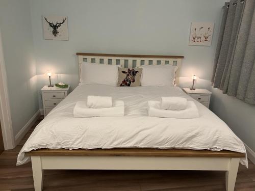 Una cama grande con sábanas blancas y almohadas. en Charming Woodland Lodge 2 person 1 bedroom, en Great Yarmouth