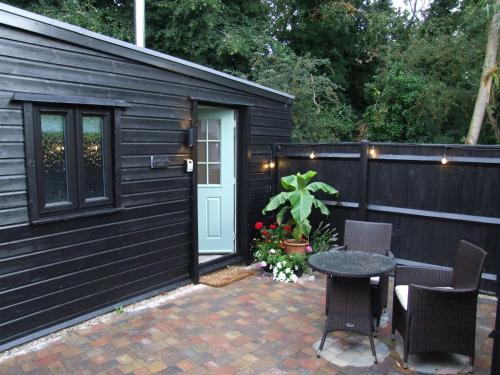 a small black building with a table and chairs at Charming Woodland Lodge 2 person 1 bedroom in Great Yarmouth