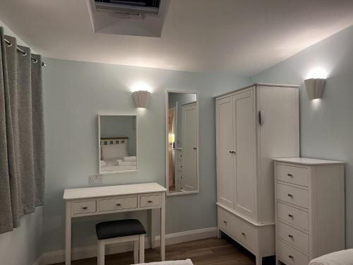 een slaapkamer met een bureau, een dressoir en een spiegel bij Charming 1-Bed Lodge in woodland setting in Great Yarmouth