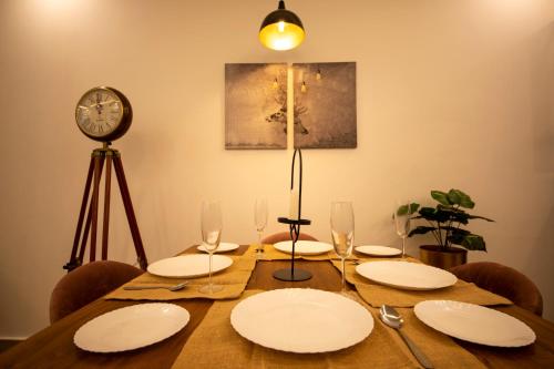a dining room table with white plates and a clock at Perfectstayz Value Homes Mussoorie 120 meters uphill in Mussoorie
