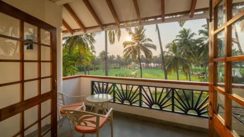 a balcony with a table and chairs and a view of a park at Novotel Goa Dona Sylvia Resort in Cavelossim