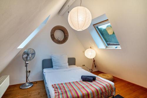 a attic bedroom with a bed and a fan at Gutshof Kaiserbacher Mühle in Klingenmünster