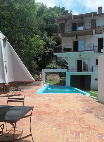 a pool with an umbrella and a house at LU'UM Master Suites in Taxco de Alarcón