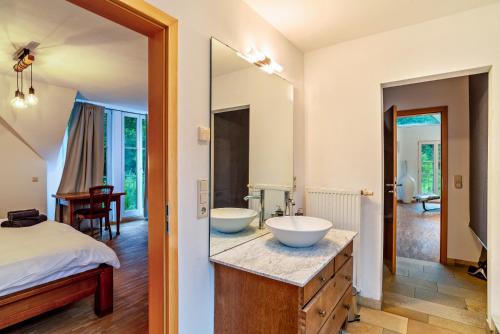 a bathroom with two sinks on a counter and a bed at Gutshof Kaiserbacher Mühle in Klingenmünster
