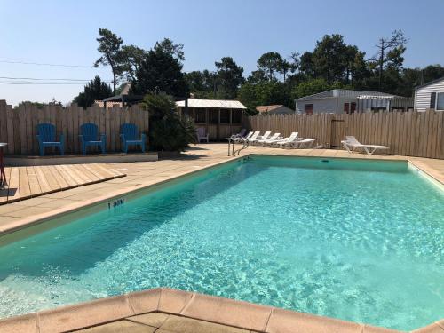 a swimming pool with blue chairs and a fence at Camping Le Logis 3 étoiles in Saint-Jean-de-Monts