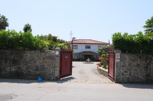a house with red doors and a stone wall at Quintinha d´Avó in Vila de Prado