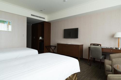 a hotel room with two beds and a desk at Fushin Hotel Taipei in Xizhi