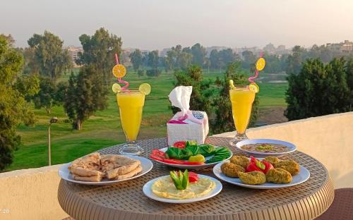 einen Tisch mit Teller mit Lebensmitteln und Gläsern Orangensaft in der Unterkunft Crystal pyramid inn in Kairo