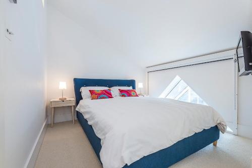 Schlafzimmer mit einem blauen und weißen Bett und einem Fenster in der Unterkunft Hidden Gem in Chiswick, Stylish 1 Bedroom House in London