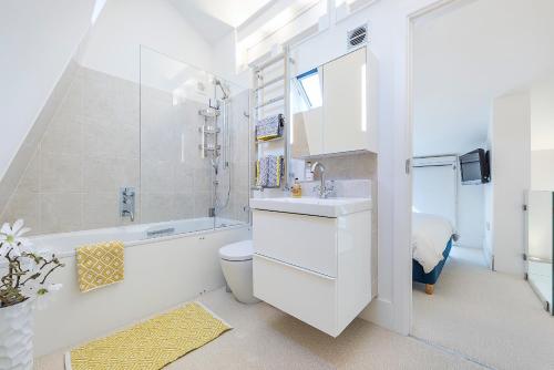 a bathroom with a sink and a toilet and a bath tub at Hidden Gem in Chiswick, Stylish 1 Bedroom House in London