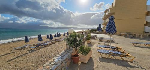 a beach with chairs and umbrellas and the ocean at Galini Beach Hotel in Kissamos
