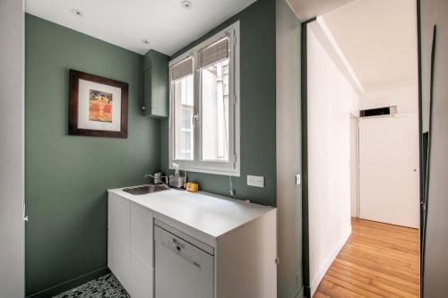 - une cuisine avec des murs verts et un évier blanc dans l'établissement Legendre - Spacieux appartement à Batignolles, à Paris