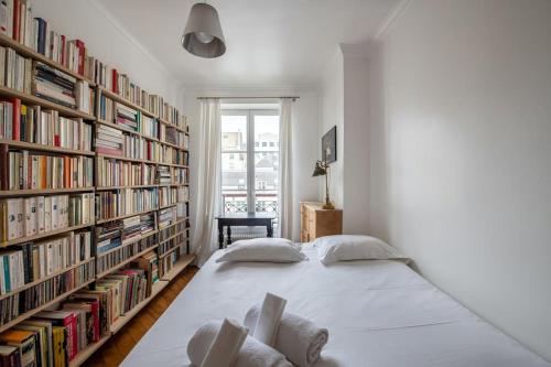 - une chambre avec un grand lit blanc en face des étagères dans l'établissement Legendre - Spacieux appartement à Batignolles, à Paris