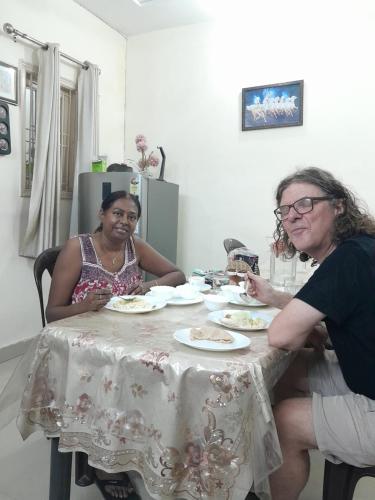 dos mujeres sentadas en una mesa con platos de comida en Bhagvati BnB Homestay Apt, en Nueva Delhi