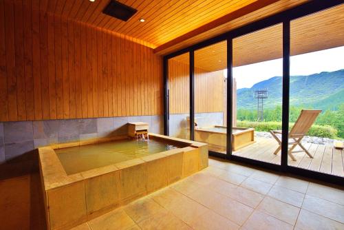 a large bath tub in a room with a large window at glampark ACONCAGUA RESORTS in Minami Aso