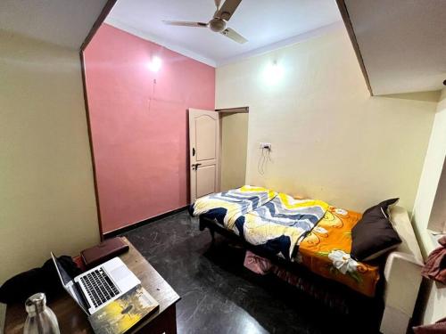 a room with a bed and a desk with a laptop at Chamundi_Temple-Hill View. in Mysore