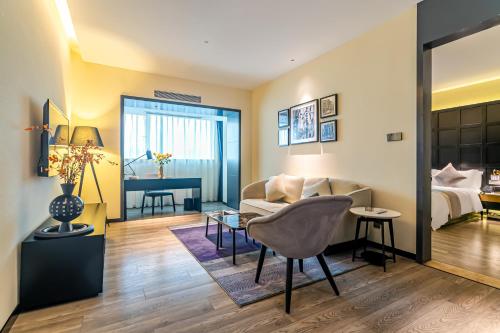 a living room with a couch and a bed at Empathy Hotel - Guangzhou East Railway Station Tianhe Sports Center in Guangzhou