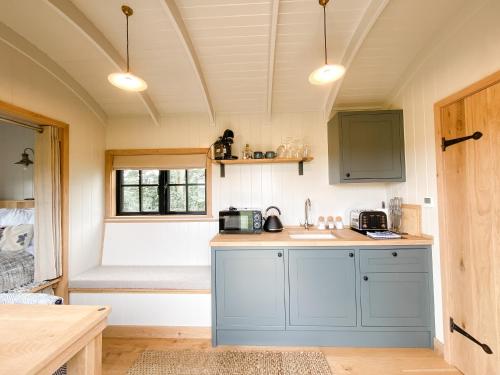 a kitchen with blue cabinets and a bed in a room at The Black Swan Shepherd Hut in Ketton