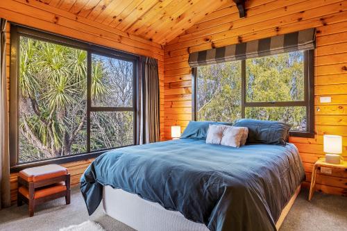 a bedroom with a bed and two large windows at Hanmer Hideaway in Hanmer Springs