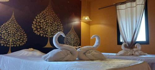 three swans made out of towels on two beds at ViphuananResort in Nong Prue