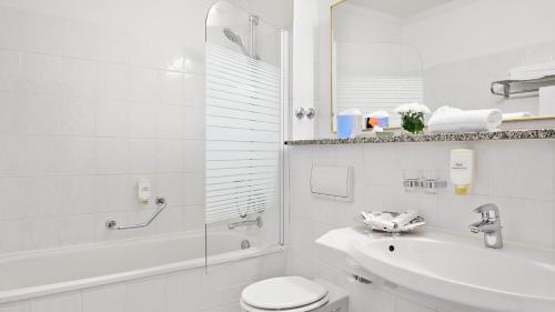 a white bathroom with a toilet and a sink at Hotel Bayerischer Hof Dresden in Dresden
