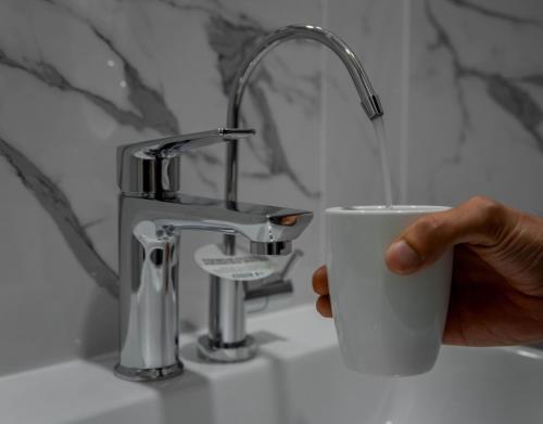 a person holding a cup next to a bathroom sink at Hotel 81 Palace - NEWLY RENOVATED in Singapore