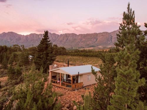 a house in the middle of a field with mountains at Vrolikheid Landgoed in Tulbagh