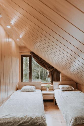 two beds in a room with wooden ceilings at Holiday home Migliņas in Kaugurmuiza