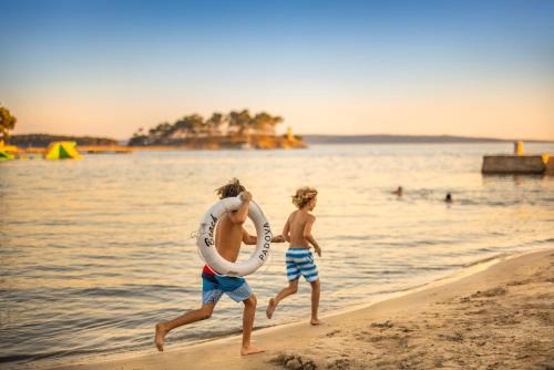 two children walking on the beach with a life buoy at Valamar Padova Hotel in Rab