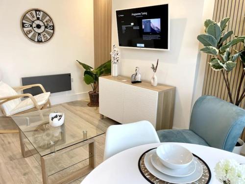 a living room with a table and chairs and a clock at Lush Porthcawl Large Spacious 2 bedroom Apt, Parking, Garden access, Prime Location in Porthcawl