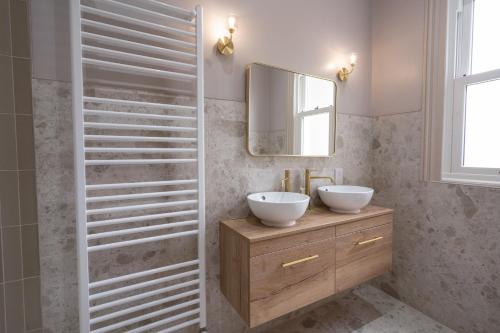 un bagno con due lavandini e uno specchio di Our House Collective - Luxury Stay in Lincoln City Centre, Hot tub, Sleeps 16 a Lincoln