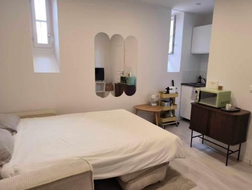 um quarto com uma cama branca e uma cozinha em Le Contemporain - Studio en hypercentre - Toulouse em Toulouse