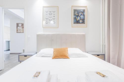 um quarto branco com uma cama grande e 2 mesas em CMG Anatole France Levallois G em Levallois-Perret