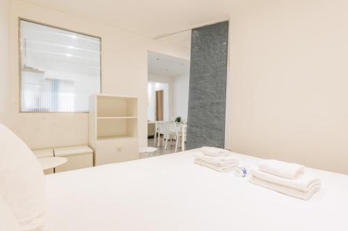 a white bedroom with two towels on a bed at CMG Anatole France Levallois G in Levallois-Perret