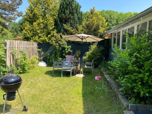 a backyard with a grill and a table with an umbrella at Haus am Grimnitzsee mit Garten in Joachimsthal