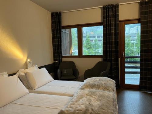 a hotel room with a bed and a chair and windows at BASE CAMP alpine apartments in Breuil-Cervinia