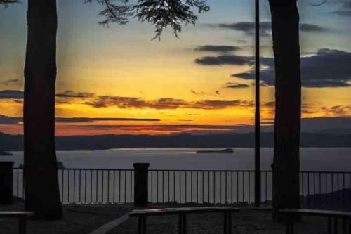 a sunset over a body of water with two benches at Appartamento Casa Armonia a Montefiascone in Montefiascone
