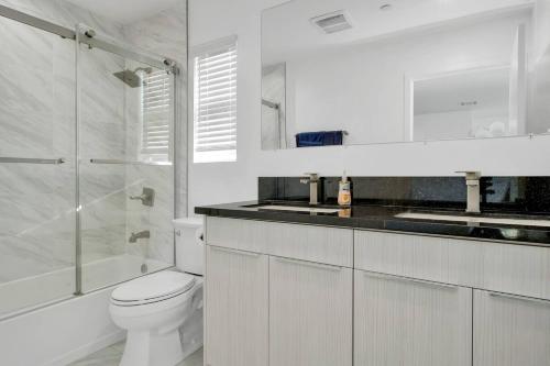y baño blanco con aseo y ducha. en Modern 3BR Home in Mid-City, en Los Ángeles