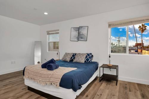 a bedroom with a bed with a blue comforter and two windows at Modern 3BR Home in Mid-City in Los Angeles