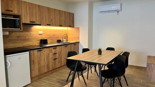 a kitchen with a wooden table and black chairs at Rezidex Apartmanház in Szeged