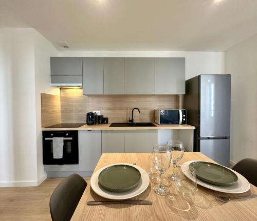 una cocina con una mesa de madera con platos y copas de vino en L'AUTHENTIQUE - Moderne - Central, en Mont-de-Marsan