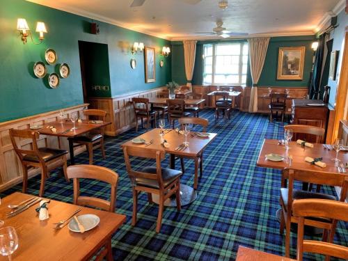 a restaurant with wooden tables and chairs and green walls at The Manor House Hotel in Oban