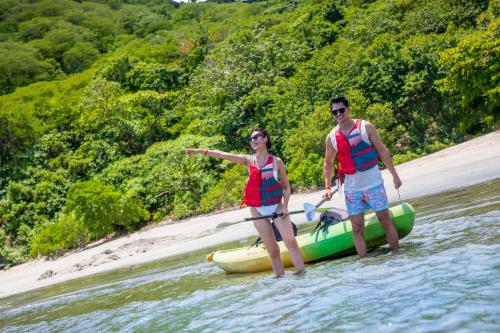 a man and a woman standing on a raft in the water at Villas Sol Beach Resort in Playa Hermosa