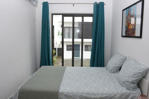 een slaapkamer met een bed met groene gordijnen en een raam bij la falaise paradis Mauritius in Flic-en-Flac
