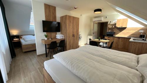 1 dormitorio con cama, escritorio y cocina en Rezidex Apartmanház en Szeged