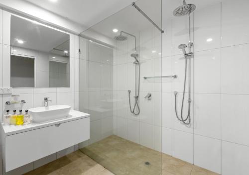 a white bathroom with a sink and a shower at Oceans Edge Beach House At Oak Beach in Oak Beach