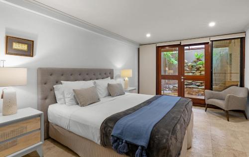 a bedroom with a bed and a chair and a window at Oceans Edge Beach House At Oak Beach in Oak Beach